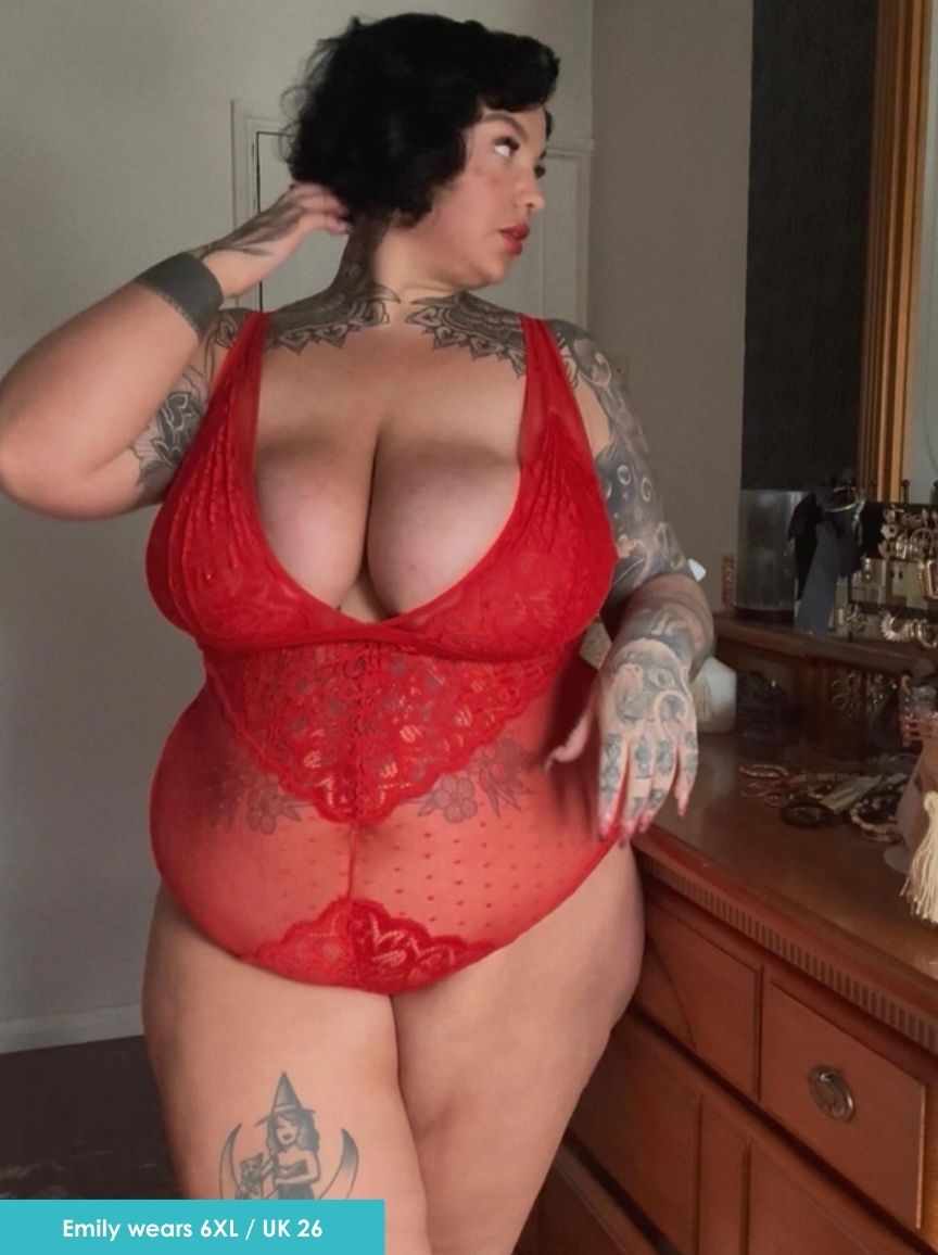 Person wearing a red lace lingerie set in a room with wooden furniture.