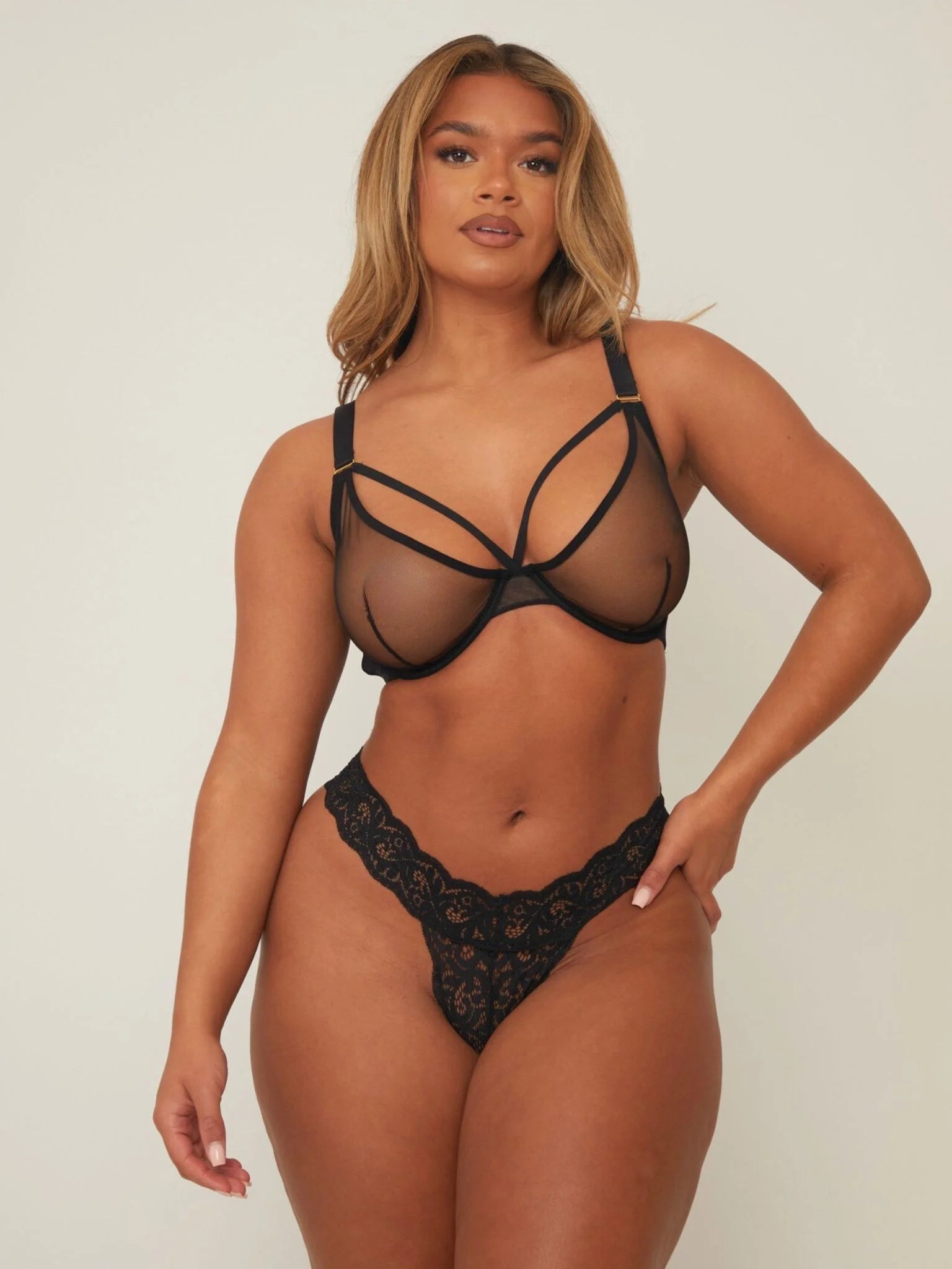 Woman wearing a black lace lingerie set against a plain background